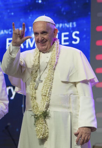 el autor del gesto es nada menos que el papa Francisco, su expresión facial es de diversión y su postura corporal de aproximación